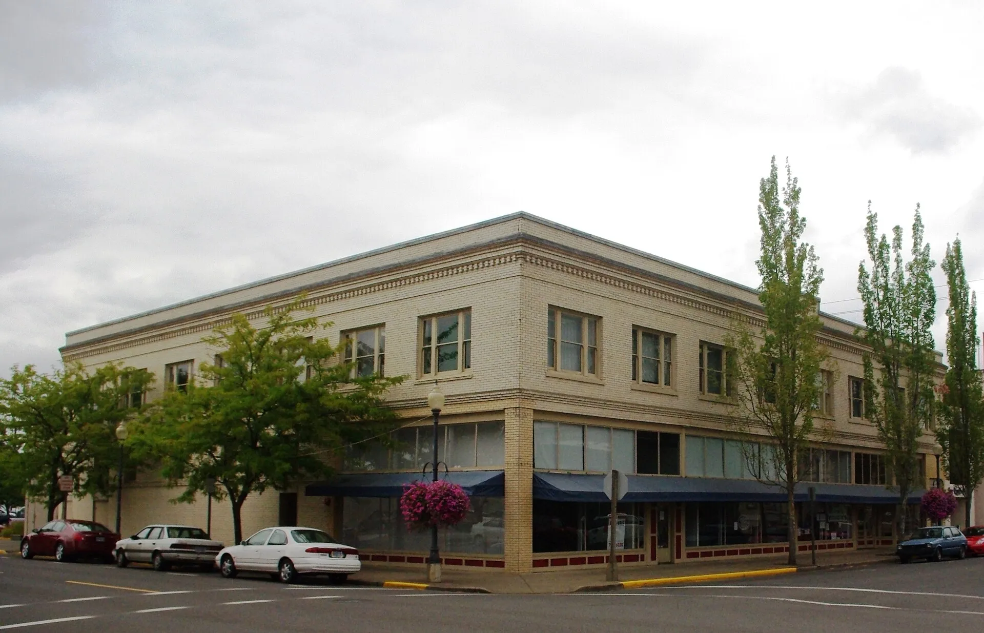 The two-story tan brick Two Rivers Market building at the corner of Broadalbin and 3rd in downtown Albany, with navy awnings over the ground-floor shops.